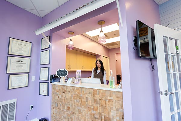 A receptionist smiling behind her desk at Howell Pediatric Dentistry