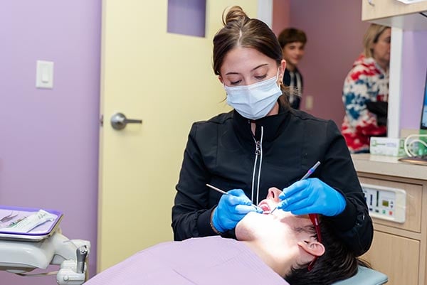A dental assistant working on a treatment on child's teeth