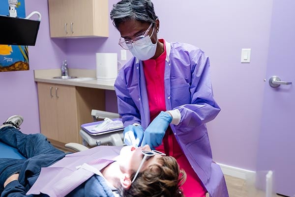 Dr. Karan Treating a kid in a dental chair Dr. Karan Treating a kid in a dental chair