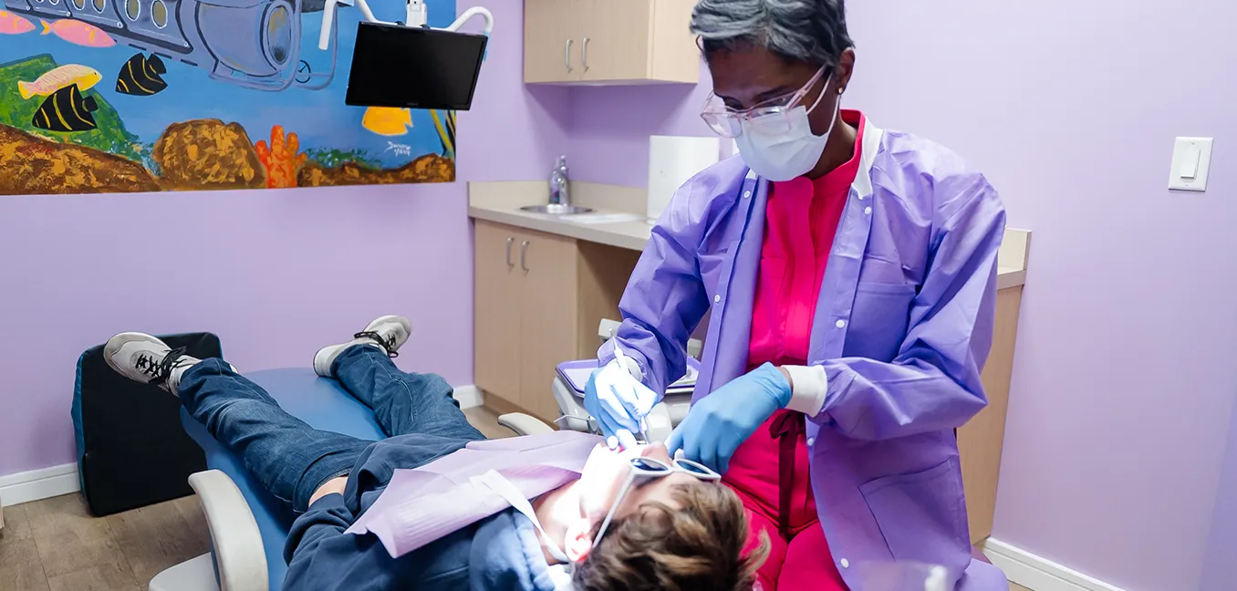 Dr. Karan Estwick performing a dental exam on a child in a colorful treatment room at Howell Pediatric Dentistry in Howell, NJ