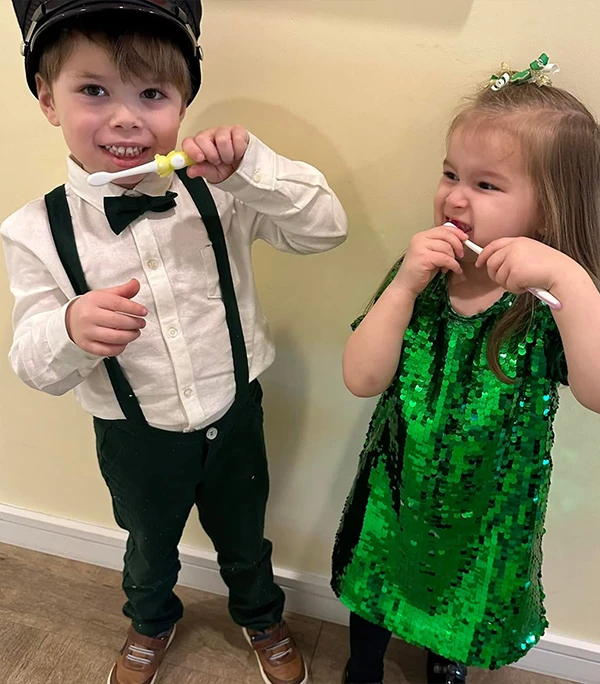 FirstVisit9 Two kids showing the action on brushing teeth in their St. Patrick's attire at Howell Pediatric Dentistry